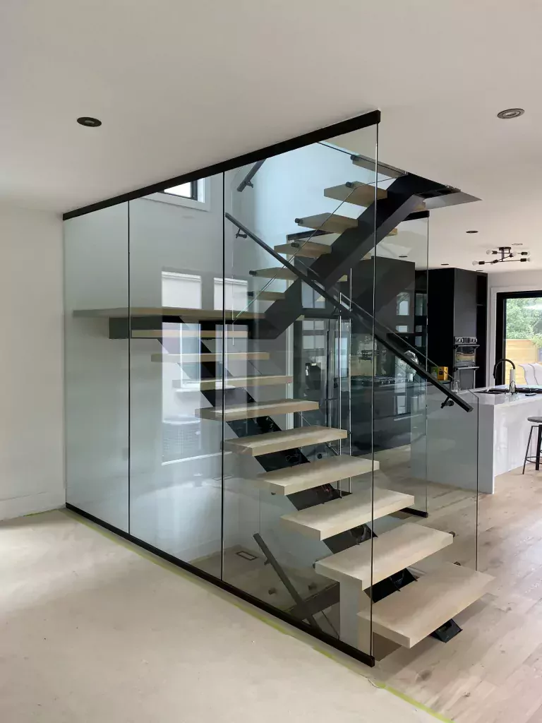 Open custom staircase with clear glass guards around the flight and upper landing