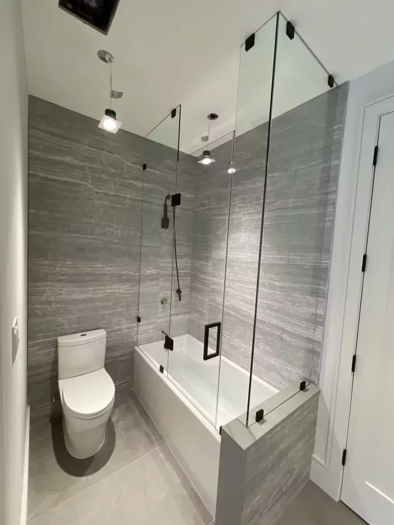 Clear glass tub shower enclosure with dark metal hardware
