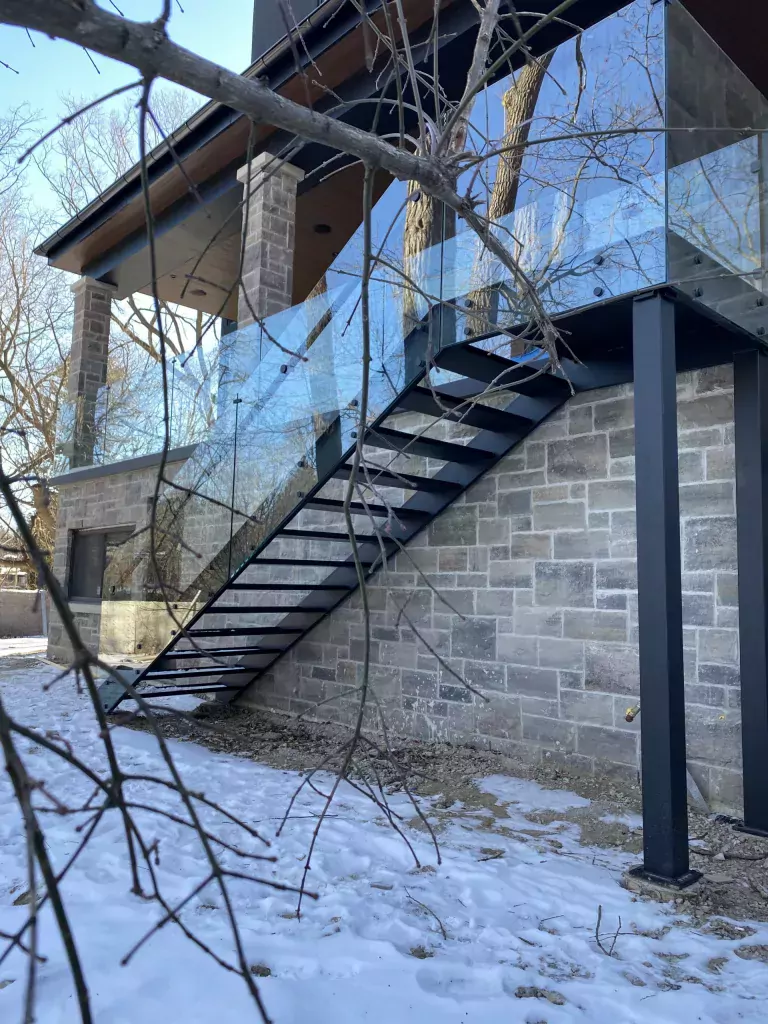 Exterior metal stair railing installed beside an elevated staircase