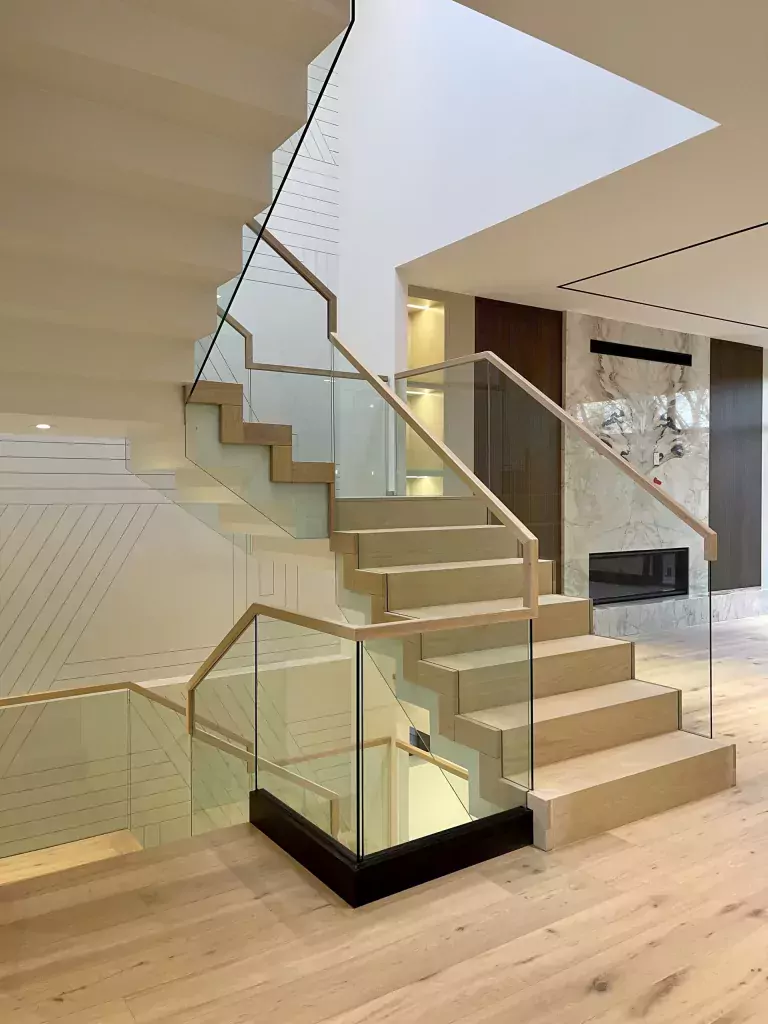 Custom interior staircase with frameless glass guards and a black base shoe