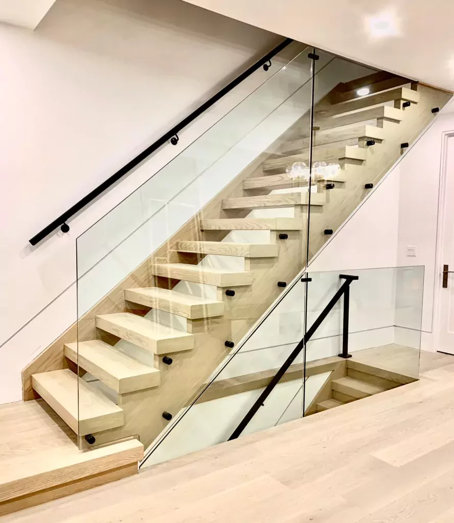 Renovated wood staircase with glass panels and black handrail details