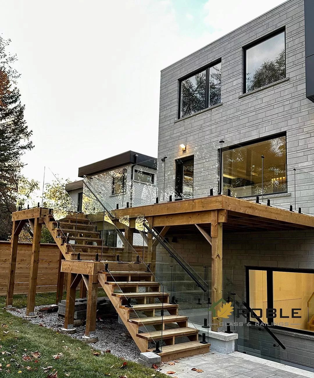 Outdoor wood staircase with glass panels and black handrails