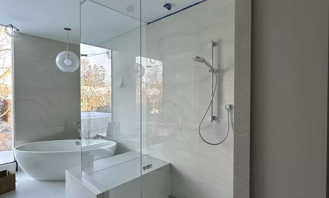 Custom clear glass shower door and fixed panel in a finished bathroom
