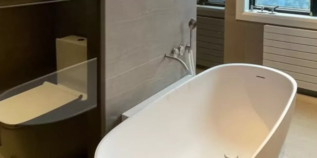 Custom glass shower enclosure beside a freestanding bathtub in a modern bathroom